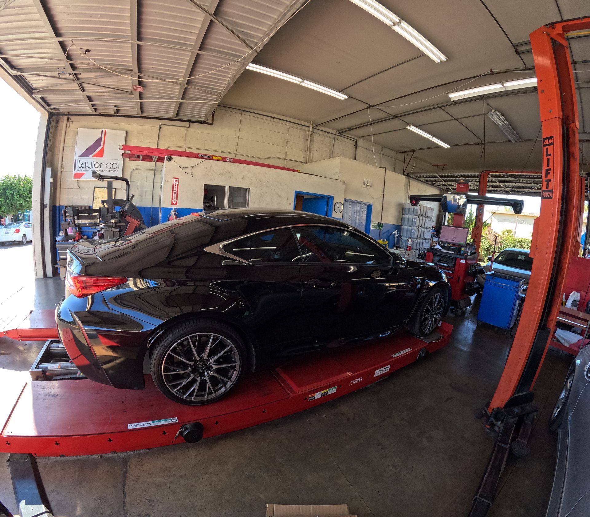 Black car on a red lift inside an auto repair shop. | Super Service of Pomona Valley