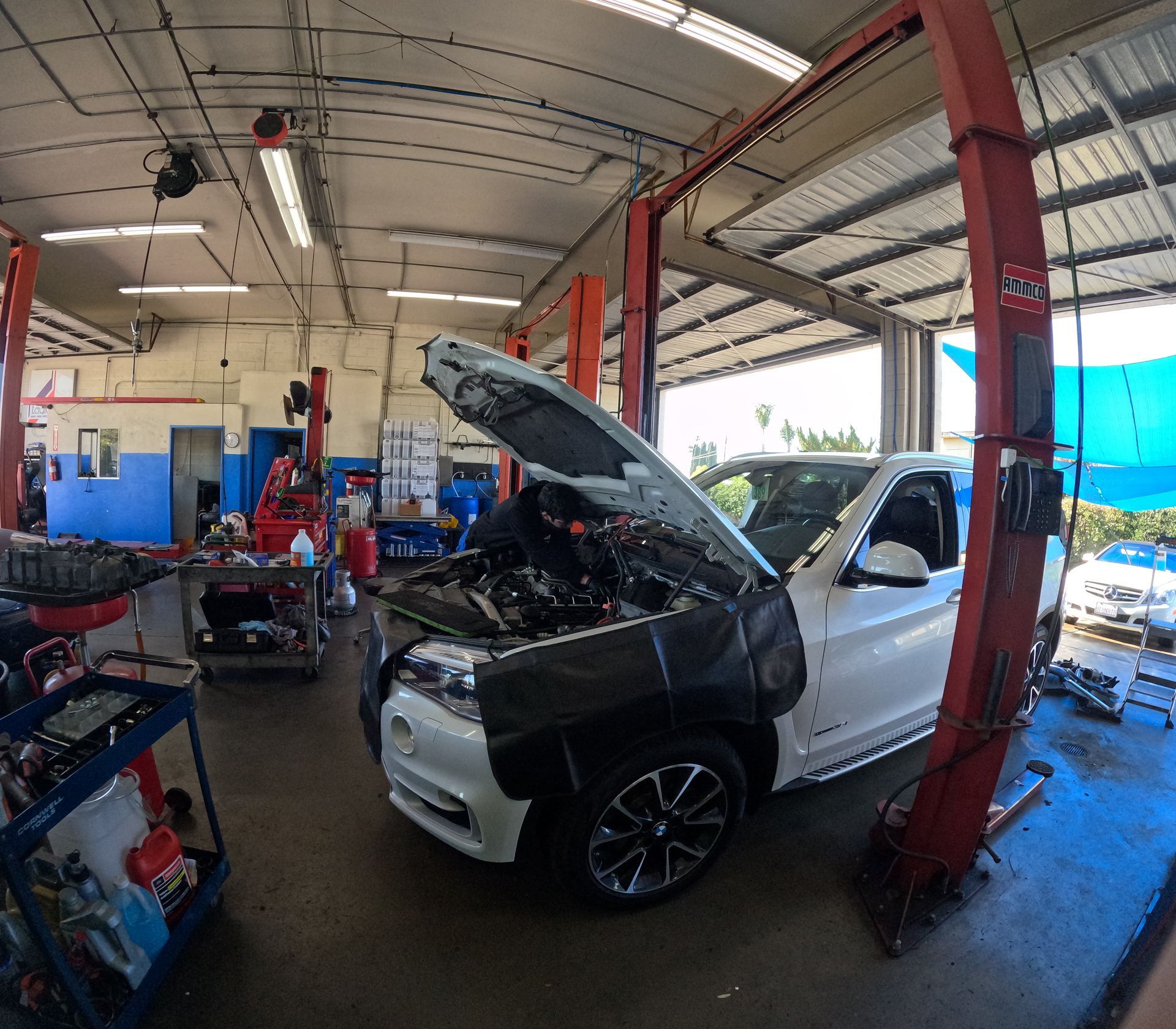 Car in auto repair shop with hood open, on a lift. Shop has tools and equipment. | Super Service of Pomona Valley