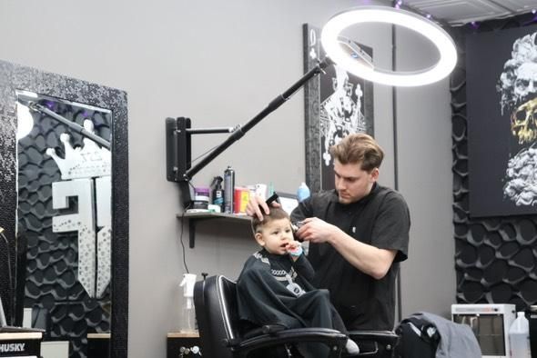 A young boy is getting his hair cut by a barber