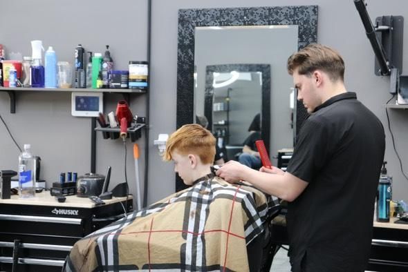 A boy is getting his hair cut by a barber in a barber shop.