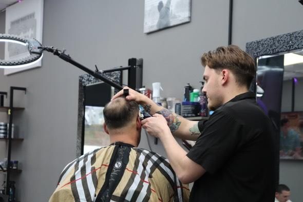 A man is getting his hair cut by a barber in a barber shop.