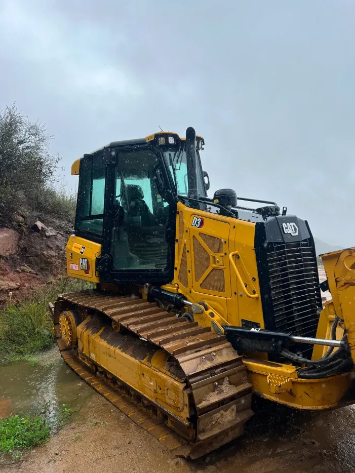 Yellow Caterpillar D7 dozer on a muddy construction site on an overcast day.
