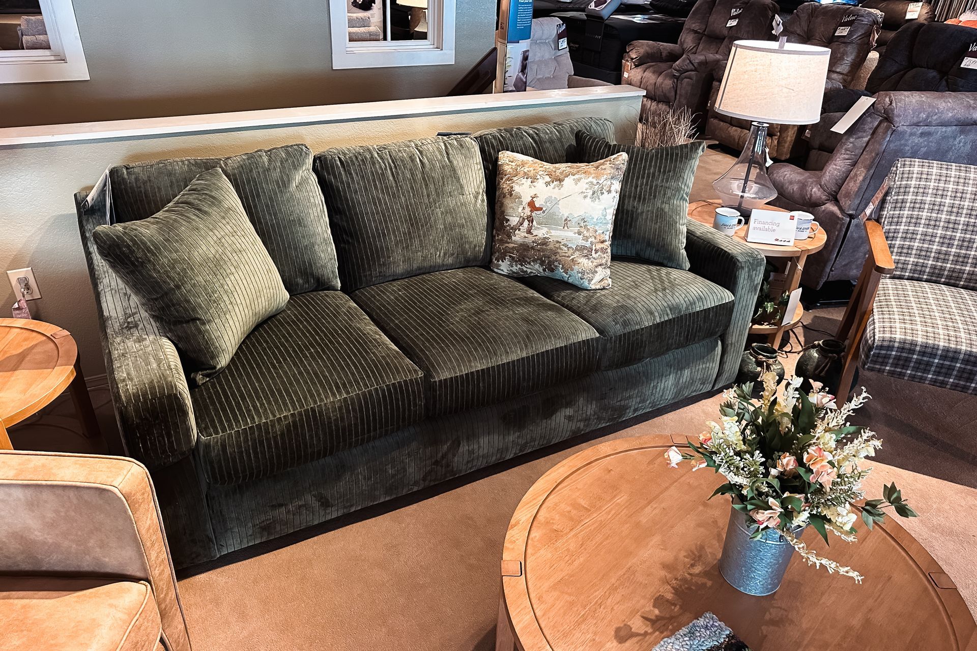 Living room with a dark green sofa, round wooden coffee table, and floral centerpiece