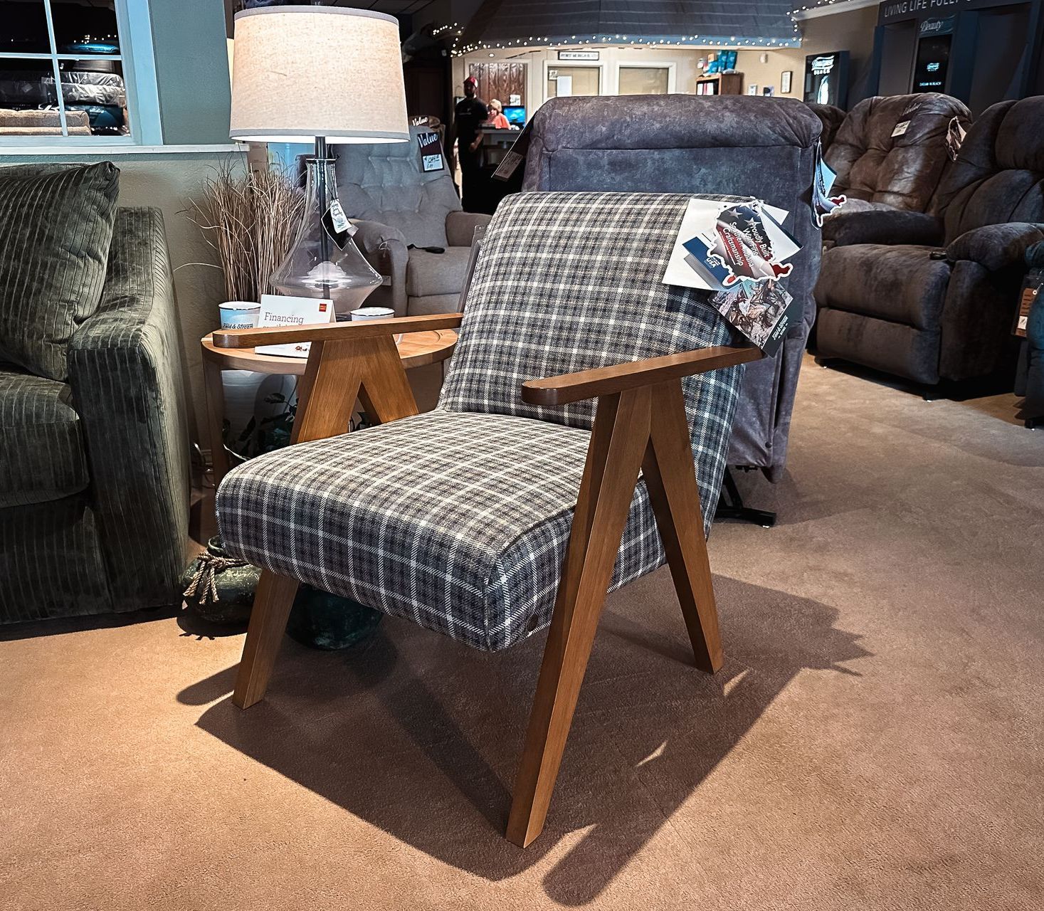 Patterned armchair with wooden arms in a furniture showroom, with lamps and sofas in the background