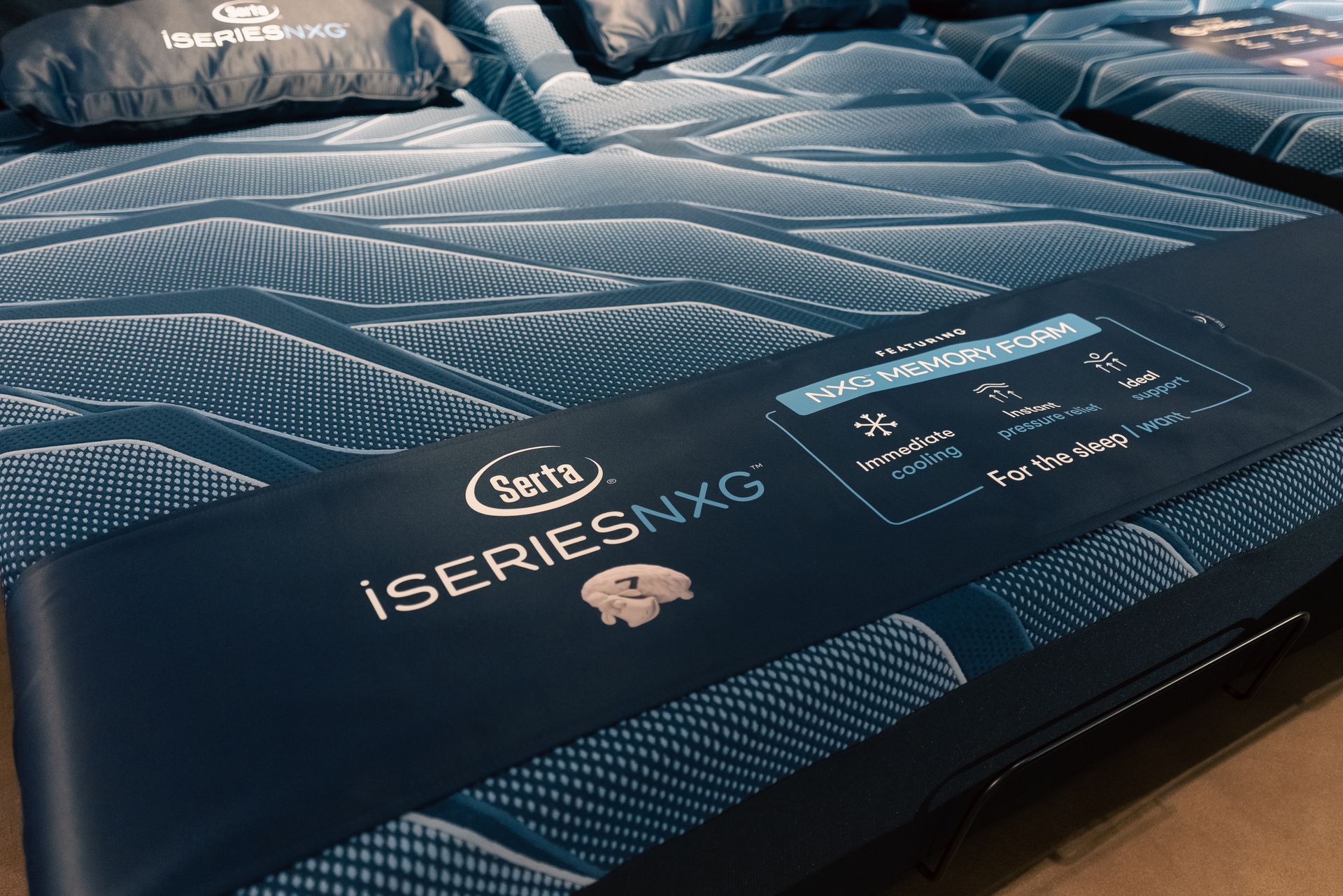 Blue patterned iSeries NXG mattress close-up with product label and quilted top surface
