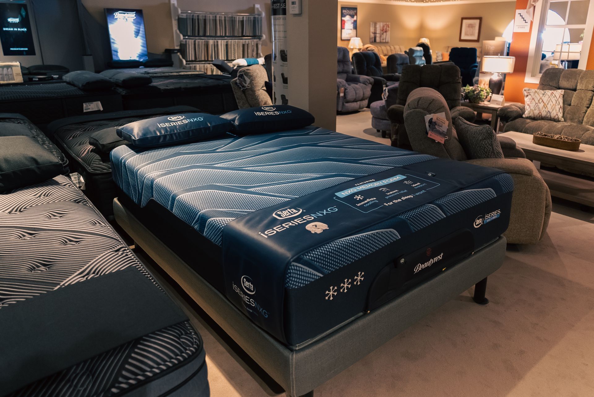 Mattress showroom with a blue patterned bed in the center and other beds in the background