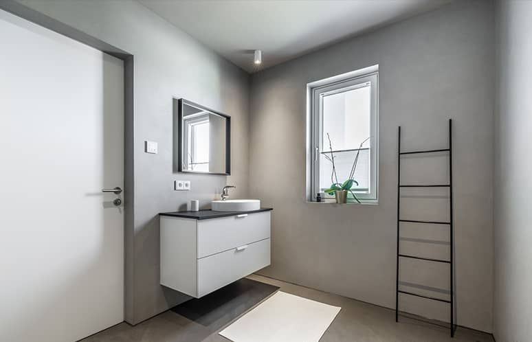 Modernes Badezimmer mit wandmontiertem Waschtisch, Spiegel, Fenster, weißen Wänden und schwarzem Leiterregal