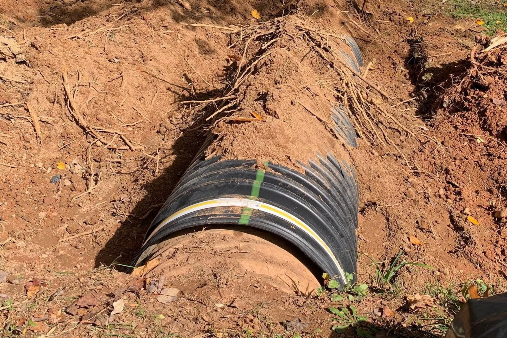 Black drainage pipe buried in dirt at a construction site