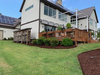 Suburban house with a wooden deck, solar panels, and a green lawn
