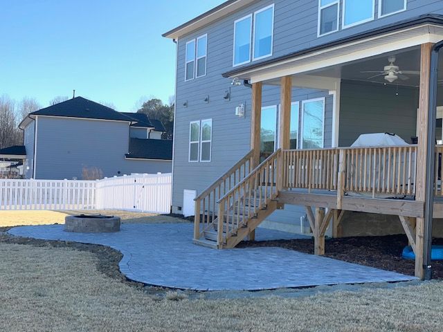 Backyard with a wooden deck, stairs, patio area, and white fence beside a house