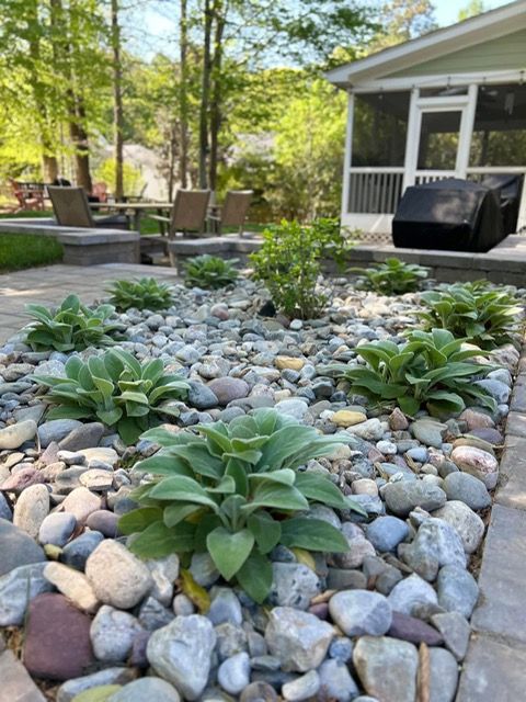Rock garden with green succulents and smooth stones beside a patio and house porch