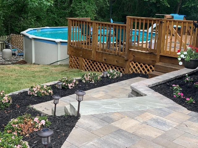 Backyard deck with above-ground pool, stone patio, and landscaped garden path