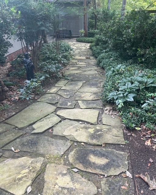 Stone garden path bordered by lush green plants and shrubs