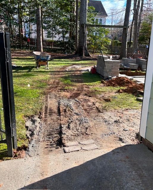 Mud track through a yard from a doorway, with grass, trees, and a bench in the background