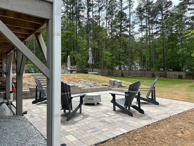 Backyard patio with black outdoor chairs, fire pit, and wooded yard beyond