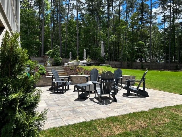 Backyard patio with chairs and fire pit surrounded by trees and a grassy lawn