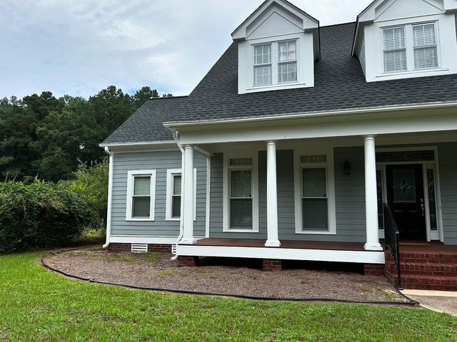 Gray house with white trim and a covered front porch on a green lawn