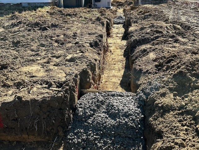 Dirt trench filled with gravel, running through a construction site