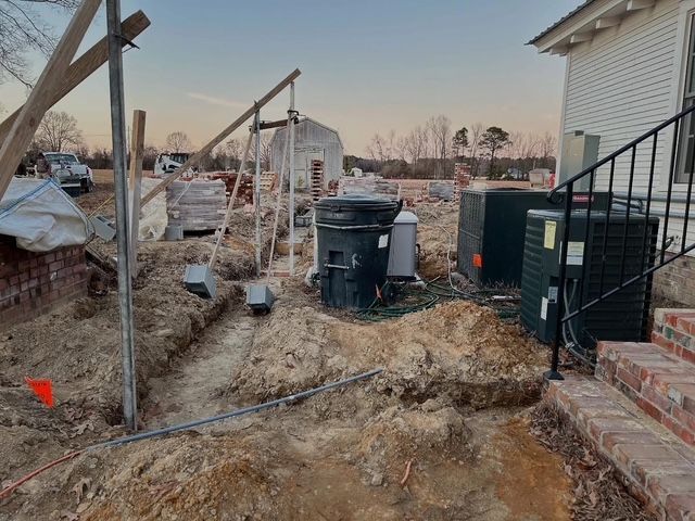 Debris-filled backyard with trash bins, broken fencing, and a house stairway at sunset