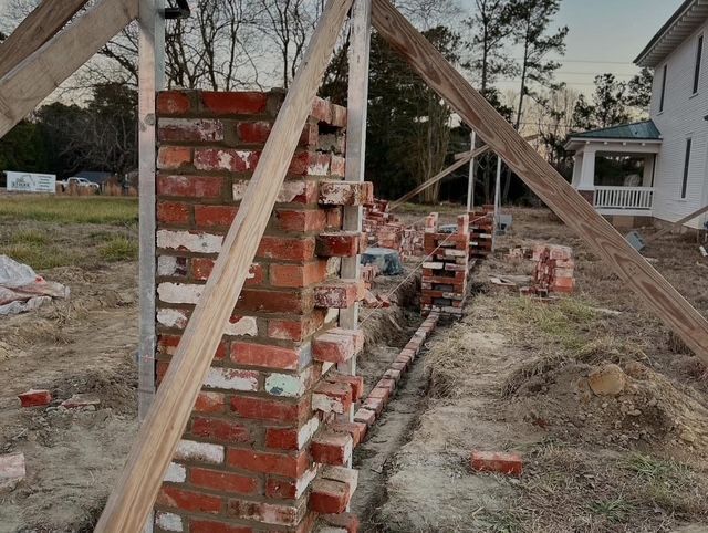 Partially built brick wall with wooden braces at a construction site outdoors