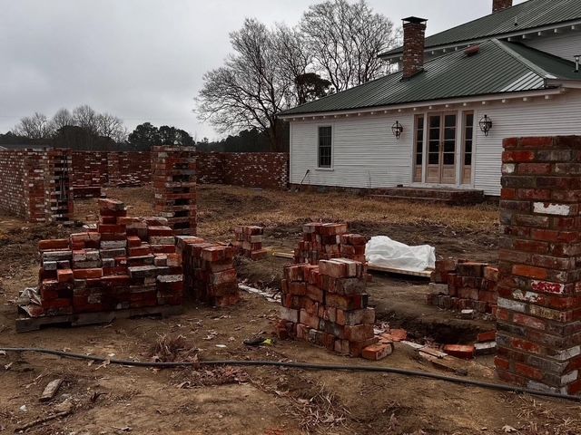 Partially built brick house with scattered brick stacks in a muddy yard