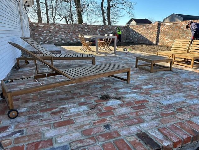 Brick patio with several wooden lounge chairs and benches in an outdoor courtyard.