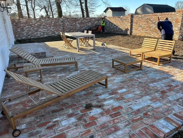 Brick patio with wooden lounge chairs and benches in a sunny outdoor courtyard