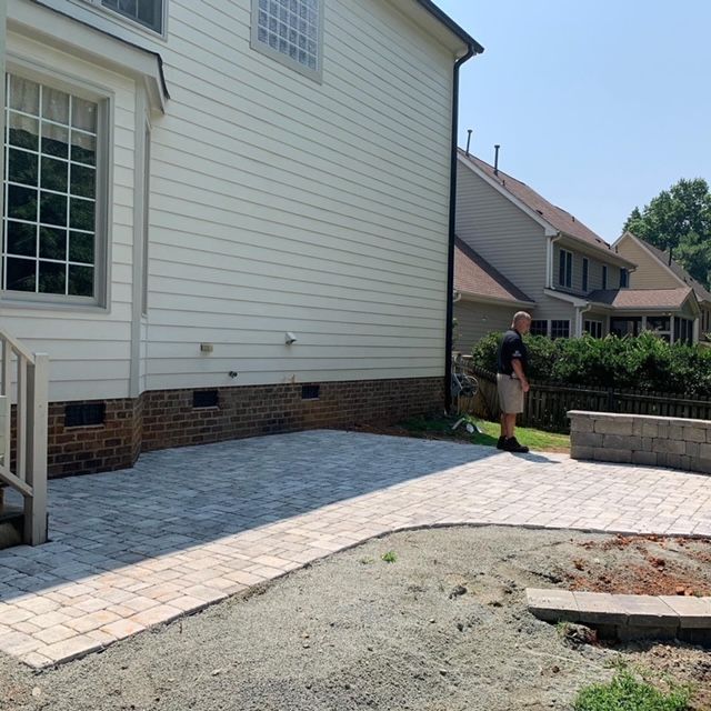 Person standing by a house beside a newly paved stone walkway and patio area