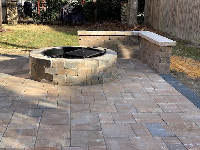 Stone backyard fire pit with built-in bench seating on a paved patio
