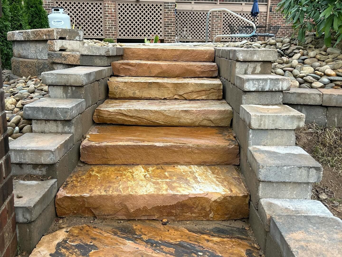 Stone outdoor staircase with uneven concrete side walls and dirt steps in a garden setting