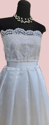 Een mannequin met een witte trouwjurk en een parelketting.