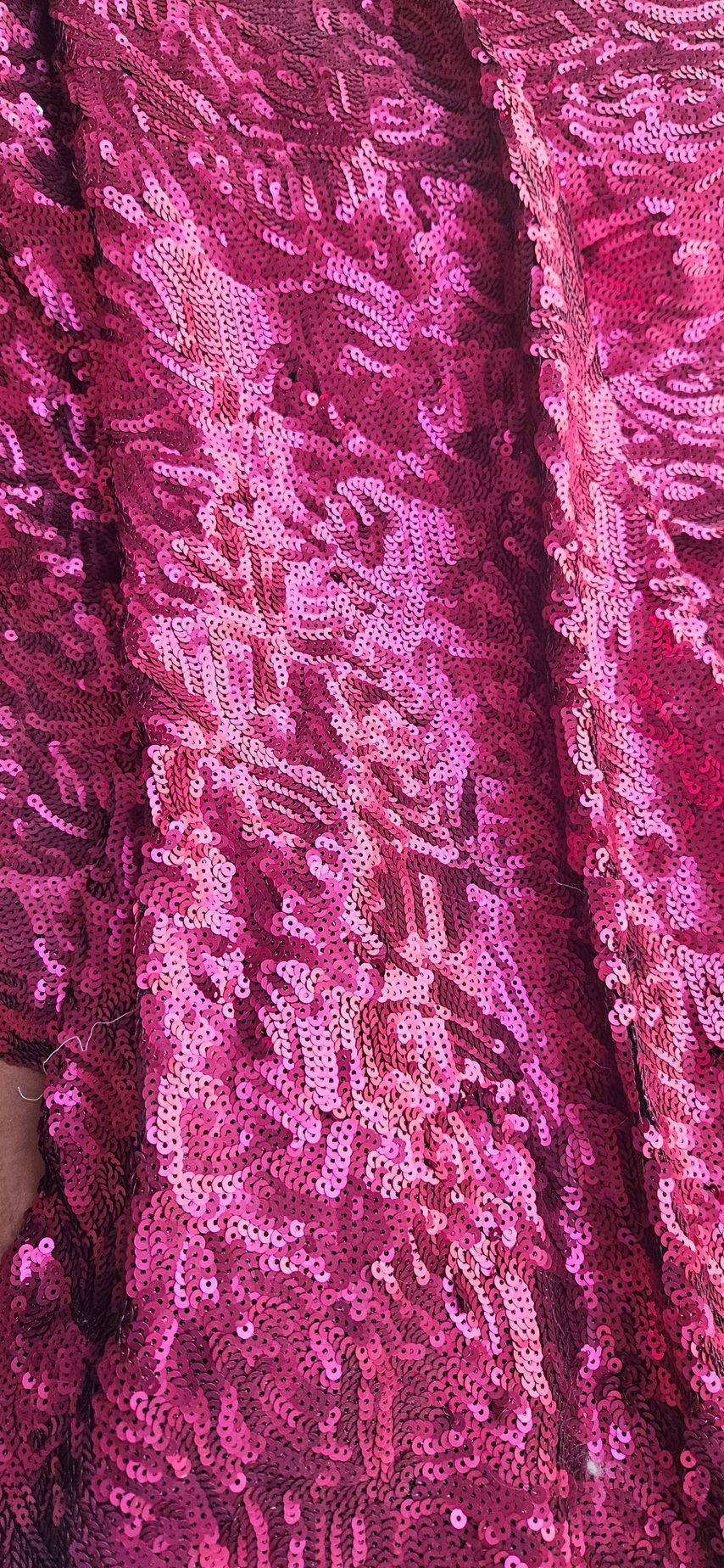 Close-up van gekreukelde magenta satijnen stof met verticale plooien en een glanzende textuur