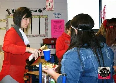 A woman is pouring a bottle of wine into a blue cup