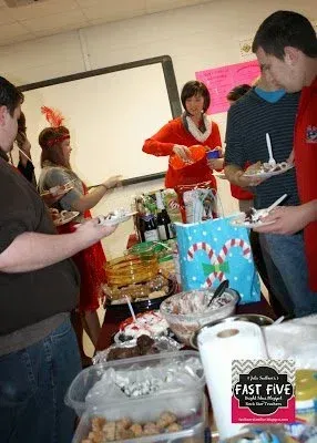 A group of people are standing around a table eating food.