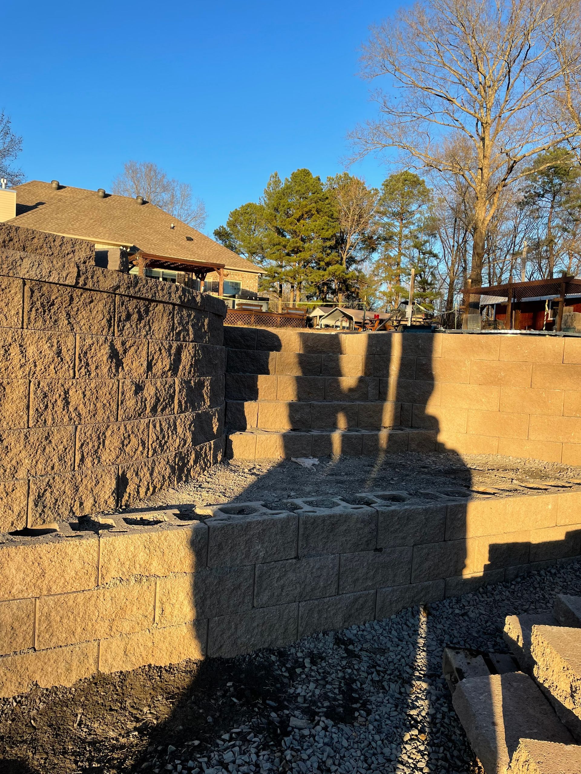 A shadow of a person is cast on a brick wall.