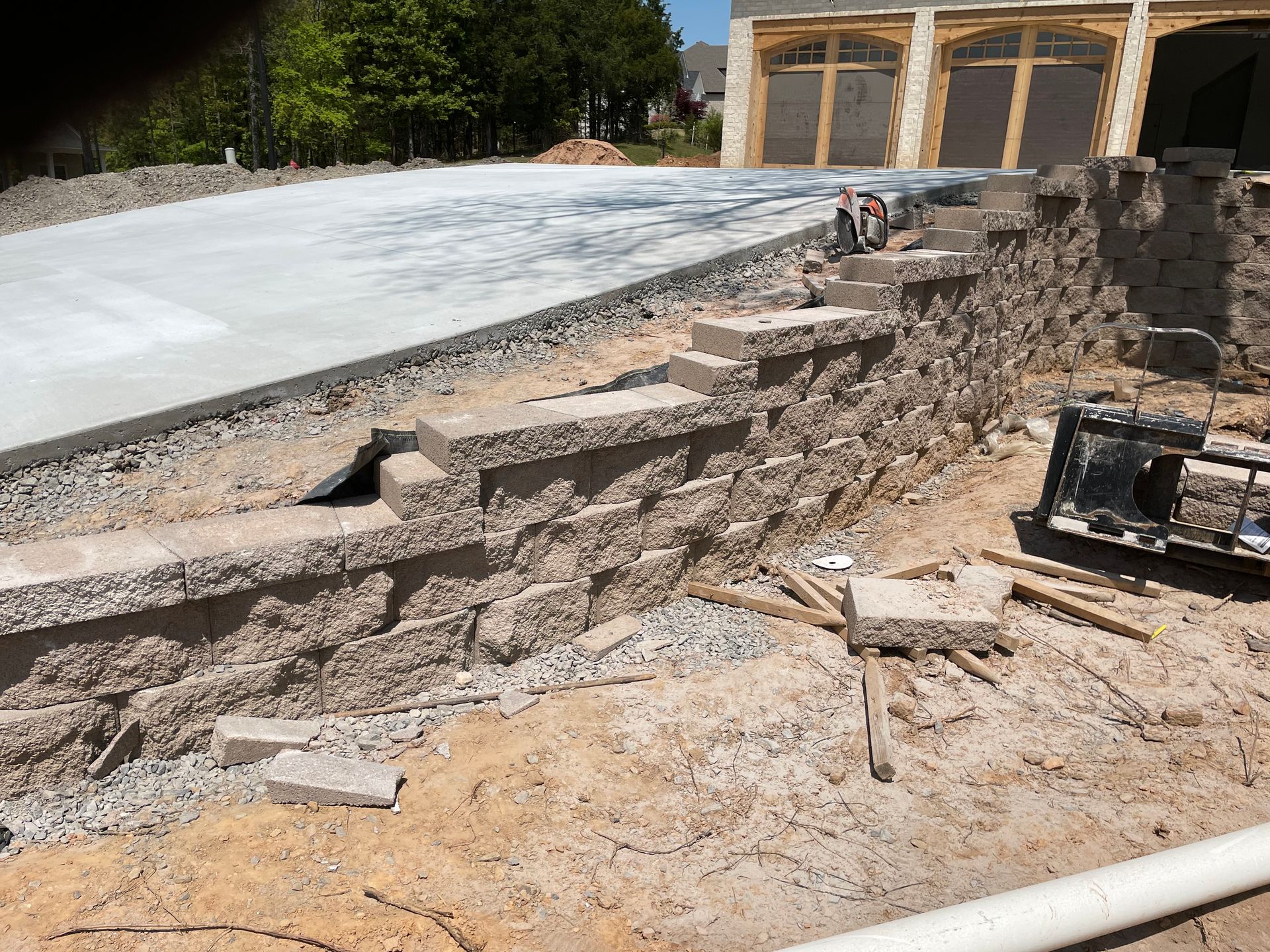 A concrete driveway is being built next to a stone wall.