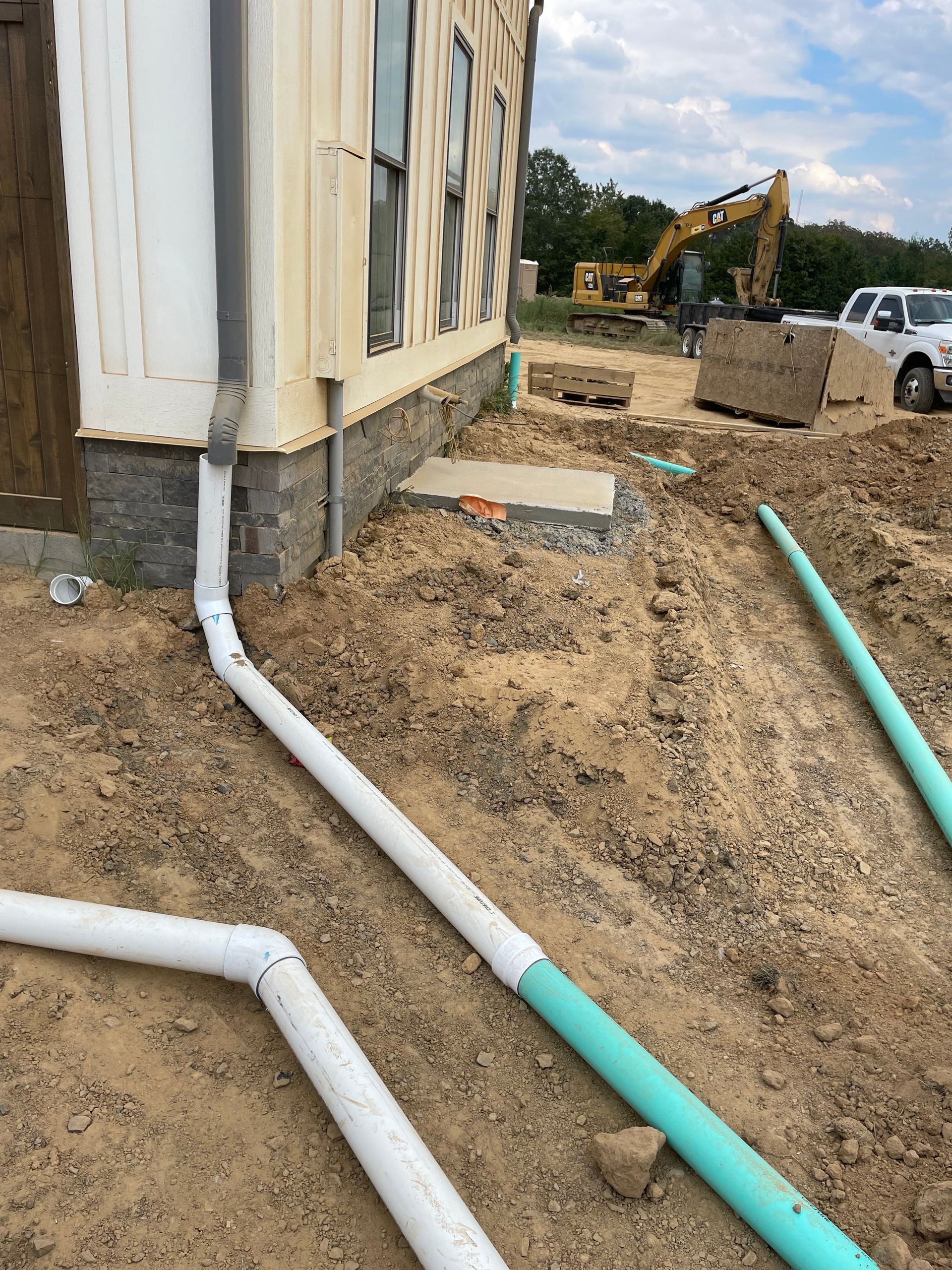 A house is being built with a lot of pipes in the dirt.