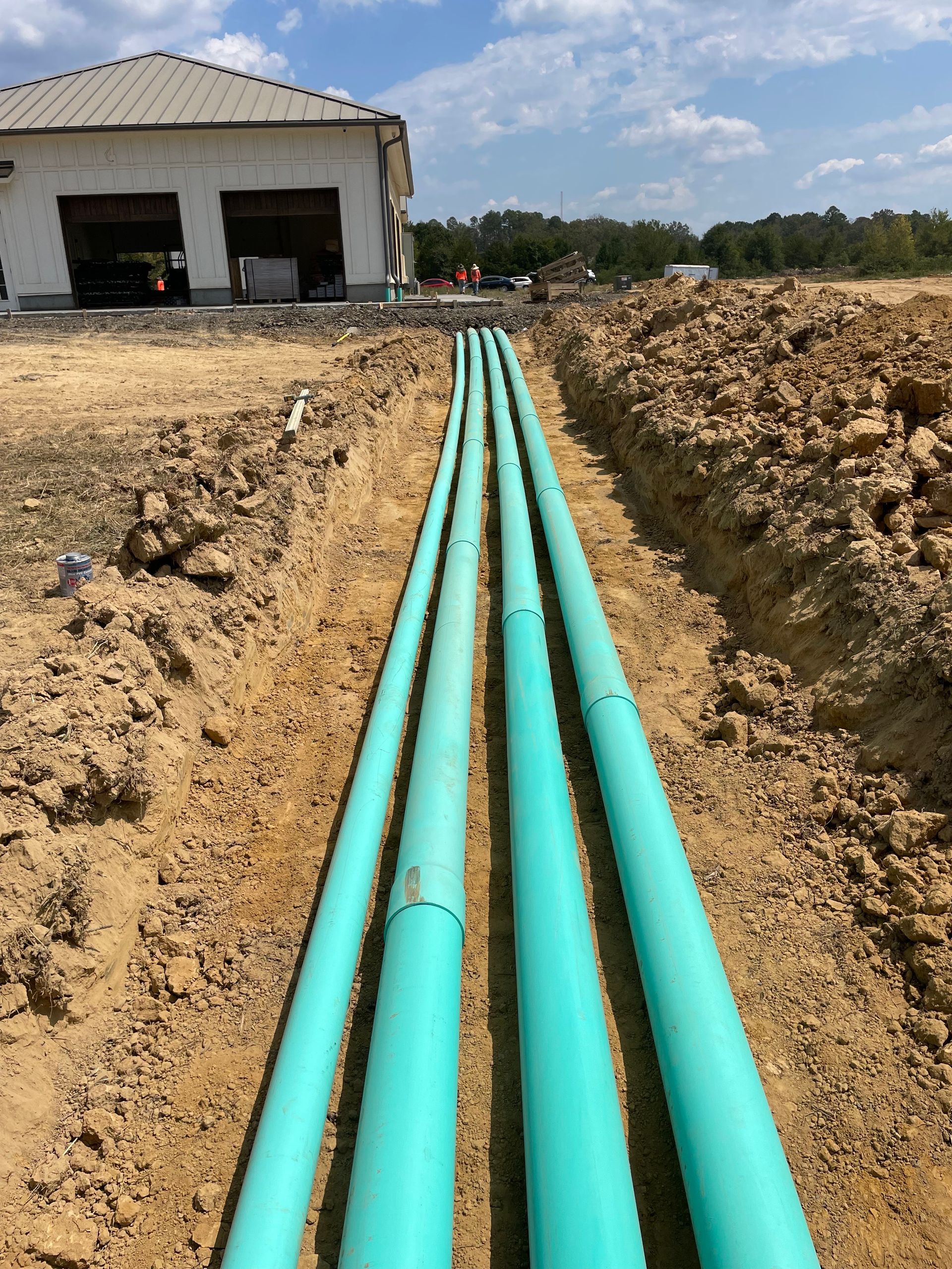 A bunch of green pipes are laying in the dirt