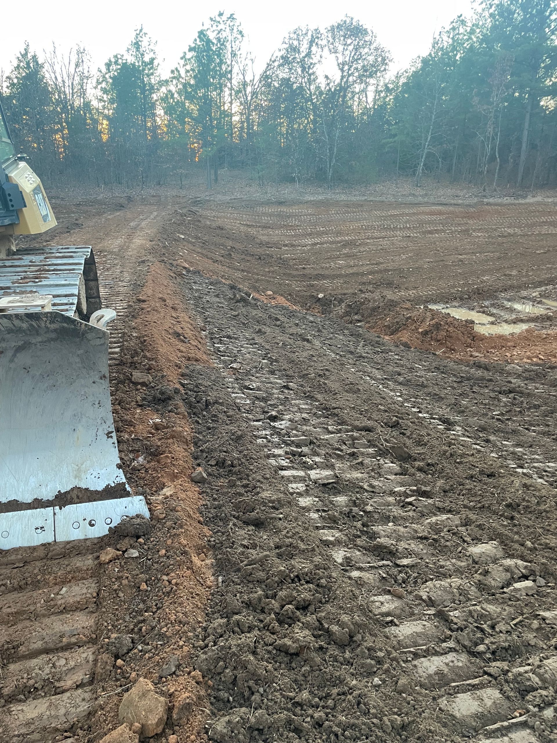 A bulldozer is driving through a muddy field.