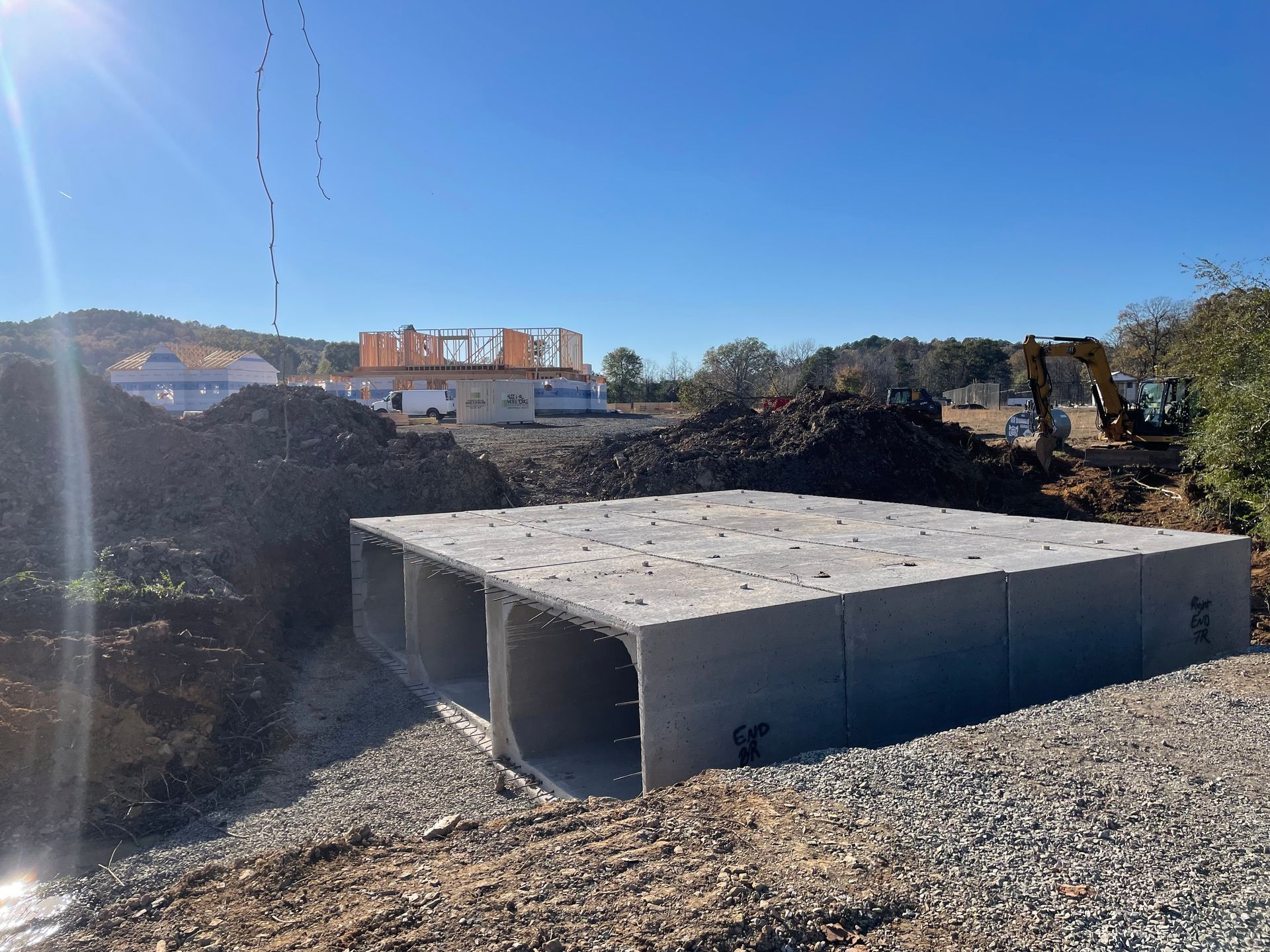 A large concrete structure is sitting in the middle of a dirt field.