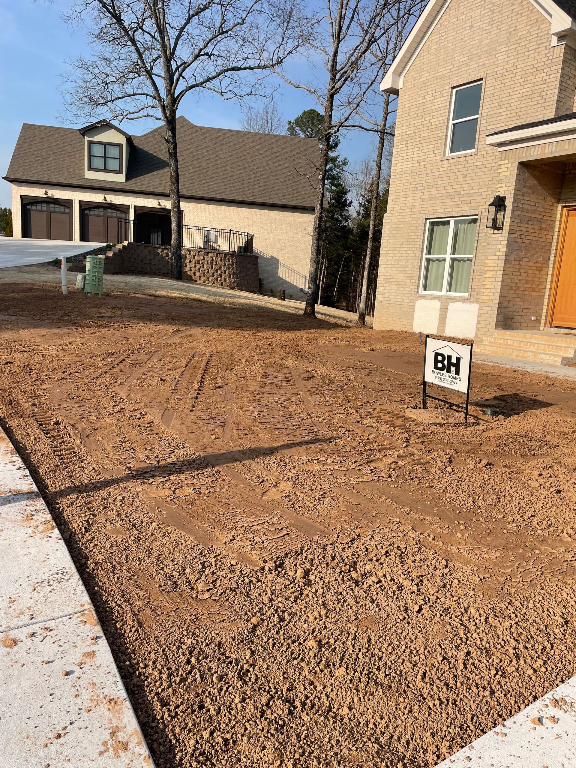 A house with a lot of dirt in front of it and a for sale sign.