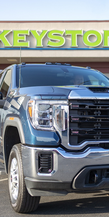 Blue GMC pickup parked in front of a Keystone dealership sign | Keystone Quality Motors