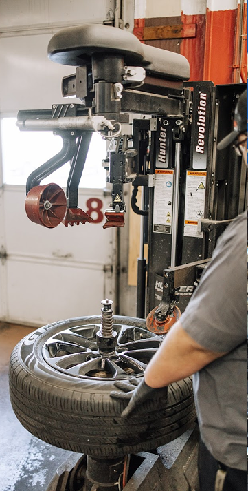 Mechanic changing a car tire with a tire-changing machine in a garage | Keystone Quality Motors