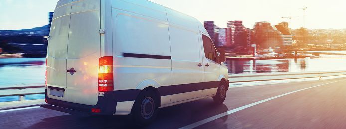 White delivery van driving on a sunlit bridge at dusk  | Keystone Quality Motors