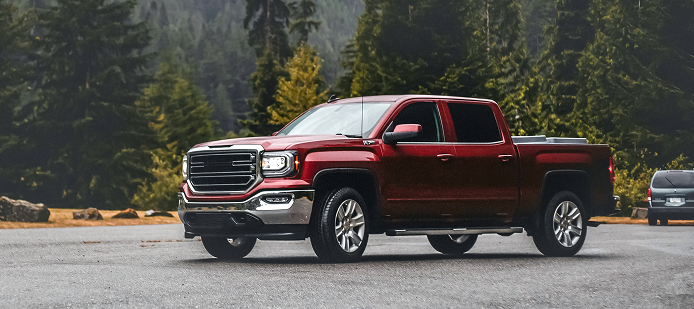 Red pickup truck parked on a road with a forested mountain backdrop. | Keystone Quality Motors