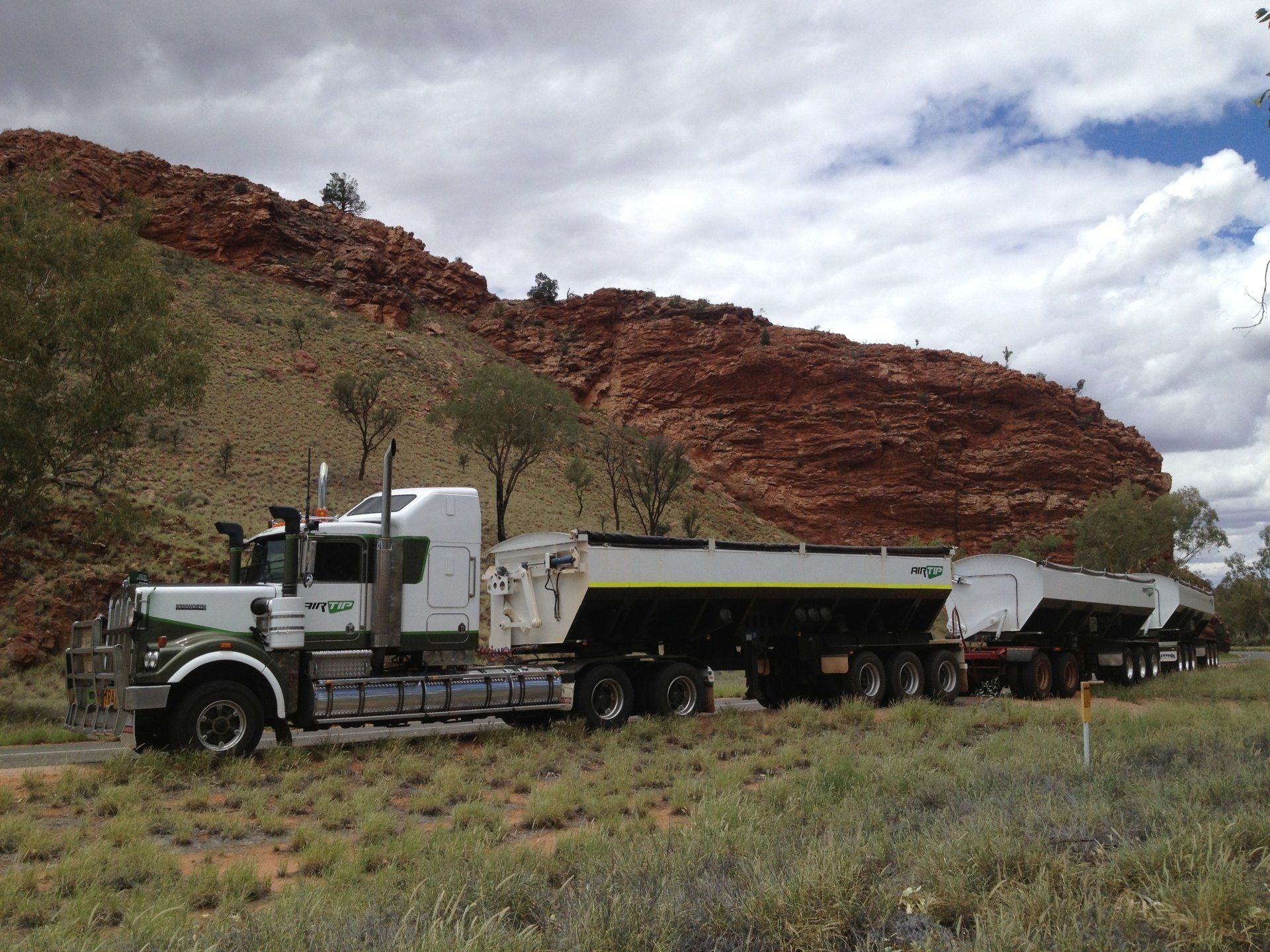White and green semi-truck hauling trailers 