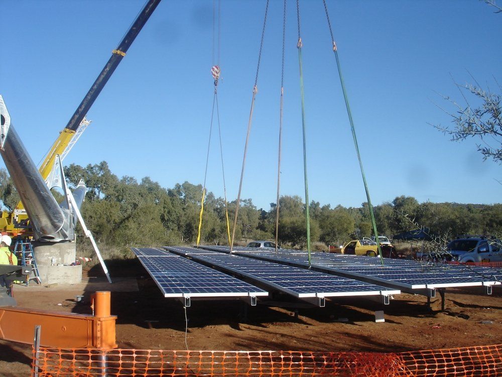 Crane lifting solar panels over a construction site.