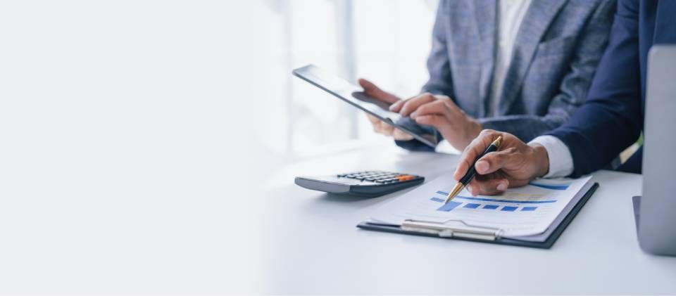 Person using a calculator and analyzing charts on a desk in an office setting