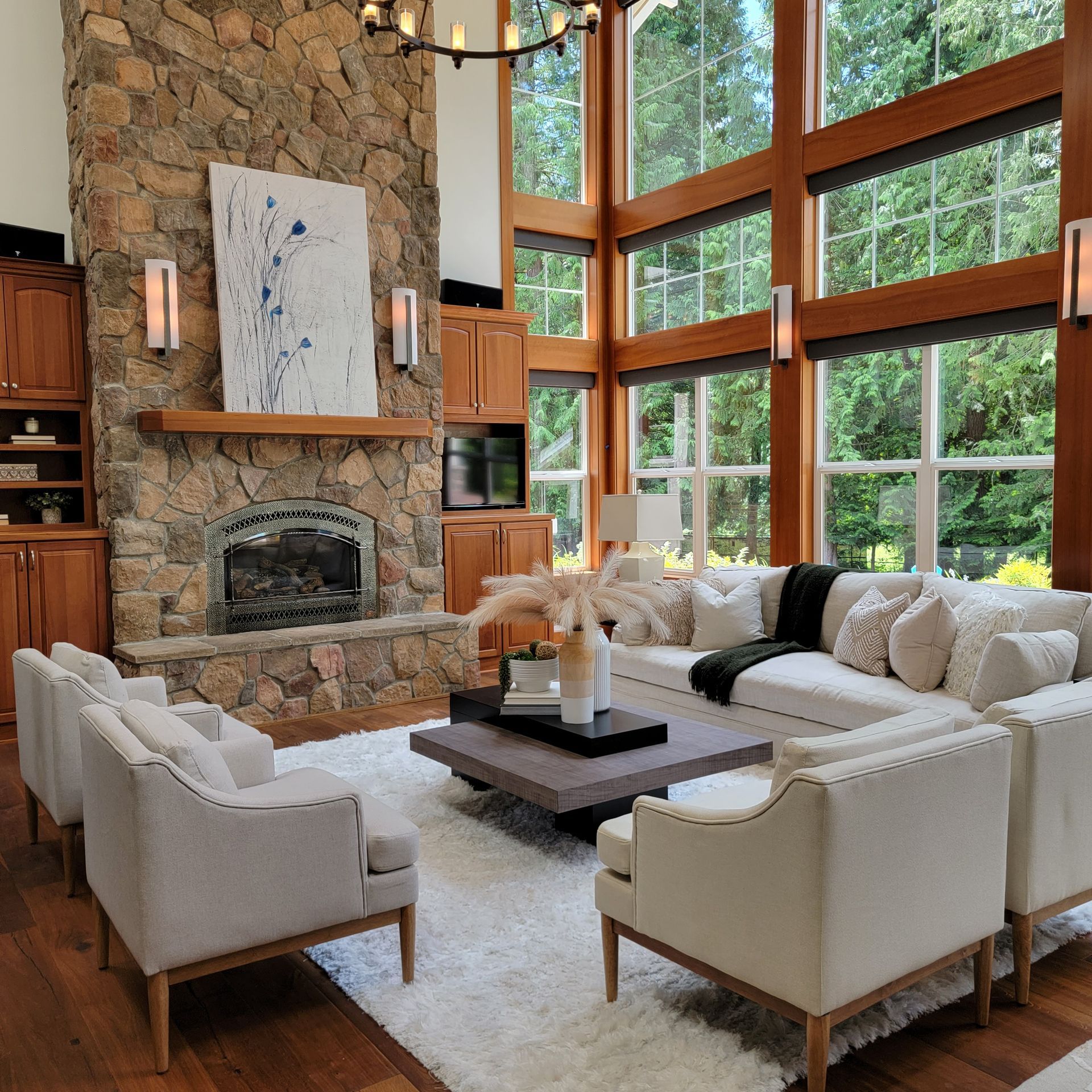 Spacious living room with stone fireplace, large windows, and cream sofas around a dark coffee table.