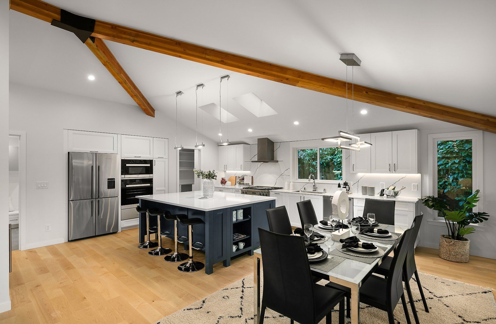 Bright modern kitchen and dining area with island, bar stools, stainless steel fridge, and white cabinetry